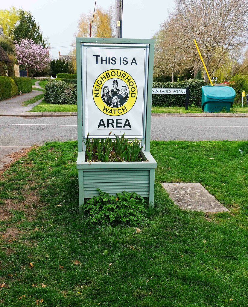 Un panel blanco moderno de Neighbourhood Watch Area a la entrada de un pueblo inglés.